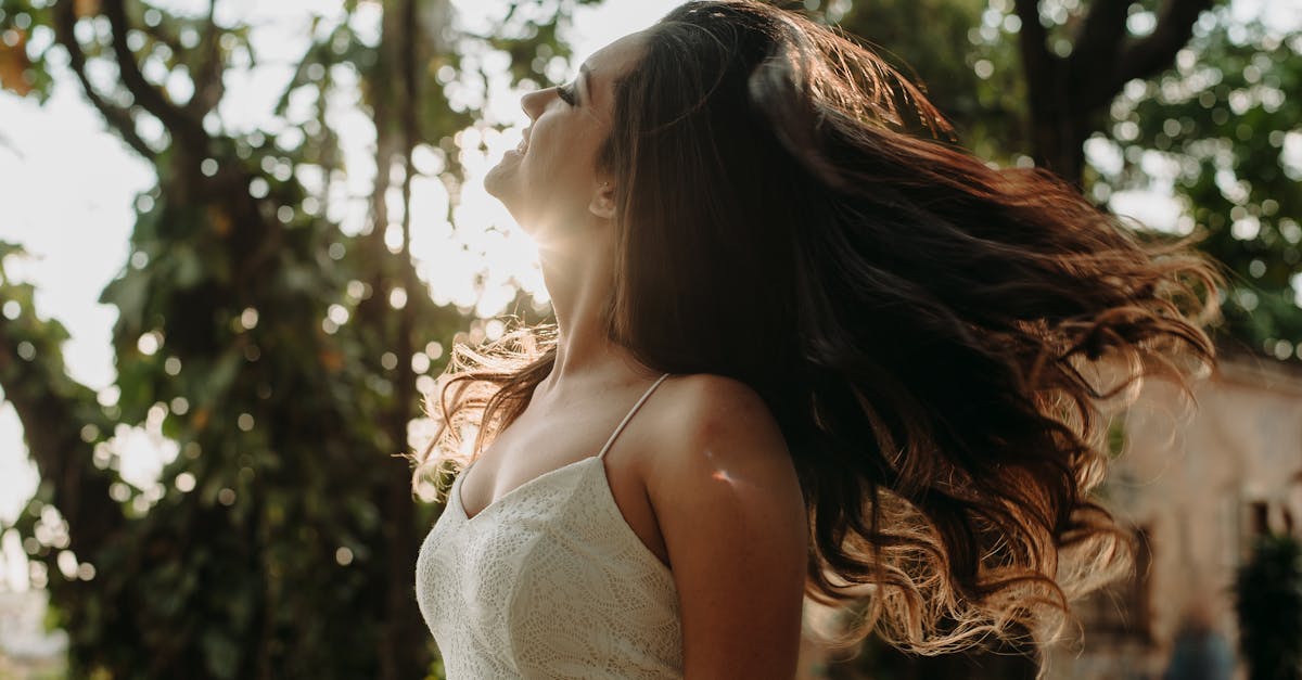 A young woman with flowing hair enjoying sunlight in an outdoor setting.