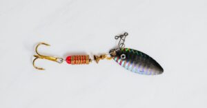 A close-up shot of a colorful metallic fishing lure with hook on a white surface.