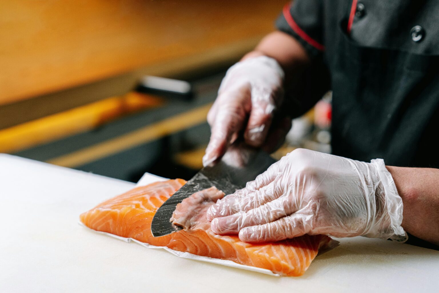 Close-up of a chef slicing fresh salmon with precision, ideal for sushi preparation.