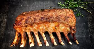 Delicious grilled spare ribs served with fresh herbs on a stone surface.