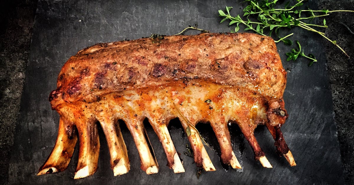 Delicious grilled spare ribs served with fresh herbs on a stone surface.